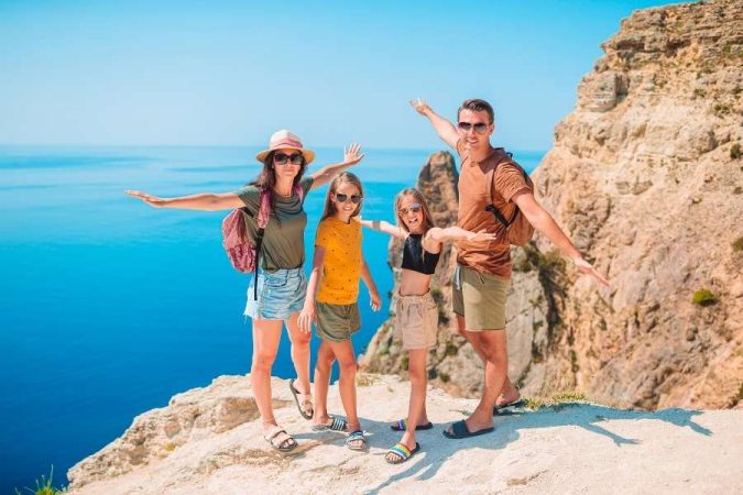 Une famille souriante profite d'une vue panoramique sur la mer lors de son premier voyage en famille.