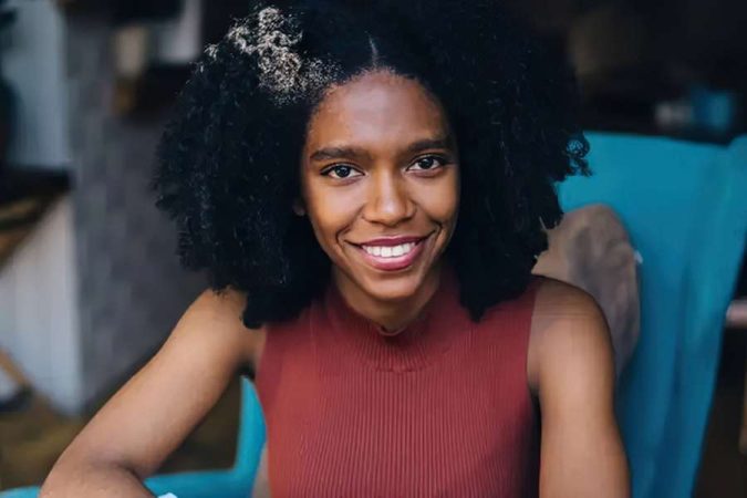 Une femme souriante avec de superbes cheveux bouclés volumineux.