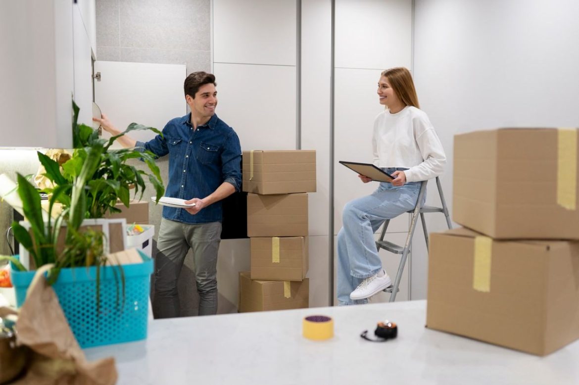 Deux collaborateurs souriants organisent des cartons lors des étapes clés pour réussir le déménagement de ses bureaux professionnels.